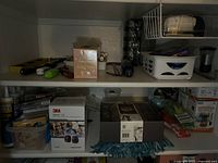 Shelf with assorted household items including the ear protection box and candle box