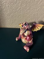 Front angle showing seated purple and pink dragon with expressive face and open mouth