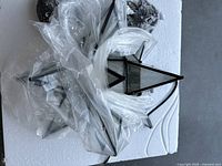 Moravian Star pendant light components with black metal frame and clear glass panels wrapped in plastic.