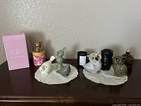 Front view of 7 ceramic animal figurines displayed on cream-colored ceramic trays including owls, birds, a black owl, a metallic lucky cat in a pink pot, and a brown small jar with lid.