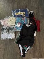 Overall clothing items laid out showing hoodies, swimwear, beanies, socks, and shorts in new condition with tags.