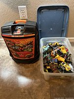 Plastic bin holding a large collection of over 100 assorted die-cast cars in various styles and colors.