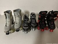 Photo showing three pairs of roller skates lined up side by side: light blue women's, gray/black kids, and black/red kids