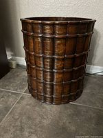 Front side view of the wood waste bin showing the segmented exterior design with gold-tone details and dark brown finish.