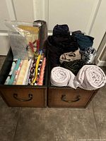 Two woven storage boxes filled with various fabric remnants and rolls of burlap, cotton, and polyester materials in multiple colors and patterns.