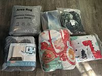 Overview photo showing the sealed packages including area rug, floor mat, and several colorful rugs or blankets with space and dinosaur themes