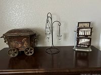 Full view of wooden decorative box, metal candle holder, and rotating photo frame arranged on a wooden surface.