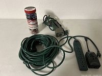 Photo showing Westinghouse extension cord coiled with timer dial and plug, Ace 6-outlet power strip, and bungee cords in container.