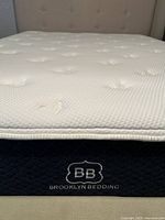 Close-up of the white pillow top mattress surface and the blue side panel with Brooklyn Bedding embroidery.