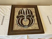 Close up photo of the African wood framed mask made from ceramic pieces, showing detail of the carved wood and ceramic design.