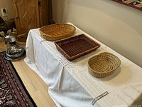 Three woven baskets on a white cloth-covered table showing size and shape differences.