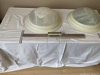 Two round ceiling flush mount fixtures placed on a white cloth-covered table, showing the domed glass shades and white bases, along with a ruler for size reference, approximately 17 inches in diameter.