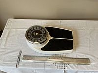 Front view of medical scale on white table with ruler for measurement reference.