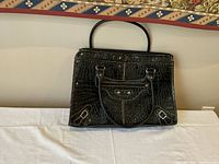 Front view of black patent leather Merona women's bag with crocodile pattern, two handles, and front zip pocket.