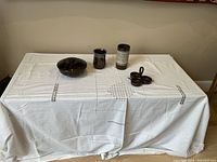 Full view of pottery items on white cloth showing bowl with lid, mug, vase, and 3-compartment dish with spoons
