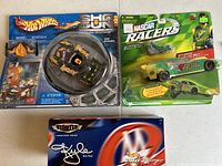 Photo showing all three items in original packaging: Hot Wheels Air Surfer, NASCAR Racers Carlos Rey, and Hot Wheels Legends Pro Racing Kyle Petty collectible.