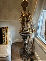 Full view of ornate floor clock statue on pedestal