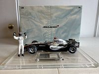 Front view of the diecast McLaren Formula 1 car with Kimi Raikkonen figure and original McLaren branded fabric backdrop.