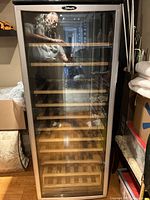 Front view of wine fridge showing glass door, stainless frame, wooden shelving