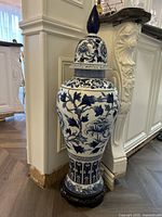 Full view of tall blue-and-white porcelain vase with lid and wooden stand
