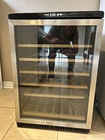 Front view of wine fridge showing glass door and wooden shelves
