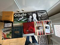 Top view showing all board games arranged on the floor including Othello, Urban Myth, Monopoly, Sorry!, backgammon, and others.