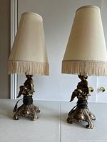 Photo showing both cherub table lamps fully assembled with lampshades on, highlighting their size and ornate design.
