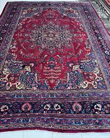 Full view of red Mashhad rug on light tile floor