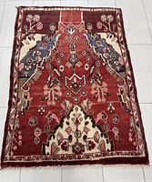 Full view of the rectangular Hamadan rug showing the full bird and floral pattern design on a deep red field with ivory and blue highlights.
