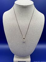 Full view of necklace displayed on bust stand against blue background
