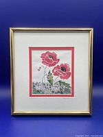 Framed art print of red poppies in gold frame against blue background