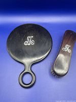 Full view of the antique ebony hand mirror and clothes brush showing their shape and silver monogram.
