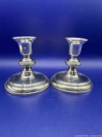 Pair of two Birks sterling silver candlesticks with EPNS bases, shown side by side against blue background.