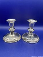 Pair of Birks sterling silver candlesticks shown from front on blue background, displaying ribbed base and collar design