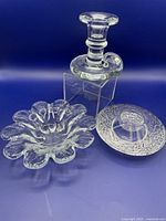 Photo showing all three glass pieces: chamber stick, petal bowl, and votive holder, arranged against a dark background for clear detail