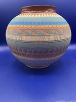 Front side view of the Navaho pottery vase showing multi-colored geometric paint patterns and large rounded shape.