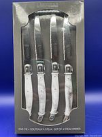Set of 4 Laguiole steak knives in original box with clear window showing marble pattern handles and stainless blades.