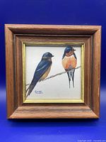 Framed artwork showing two barn swallows perched on a branch, signed by Maureen Thompson.