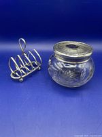 Overview of the three silver items including cut glass dispenser with silver top and heart shaped toast rack