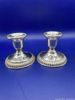 Pair of Birks sterling silver candlesticks shown from front with their weighted bases and beaded rims visible.