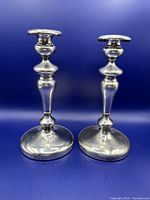 Pair of tall silver plate candlesticks showing design and height against blue background.