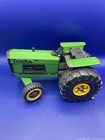 Side view of vintage green Tonka tractor showing wheels, body, and missing steering wheel