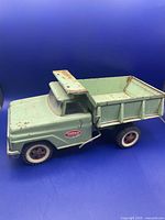 Front side view of the green Tonka Mighty Dump Truck showing rust spots and original paint wear.
