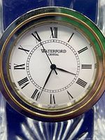 Close-up of clock face with Waterford Crystal branding, Roman numerals, and black hands
