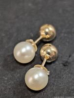 Pair of reversible 10K gold earrings with freshwater pearls seen from the front.