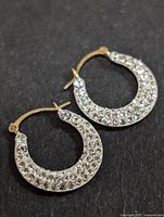 10K gold small hoop earrings encrusted with round clear cubic zirconia stones, front view.