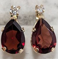 Front view showing pear-shaped garnet drops and round white top stones set in 10K gold