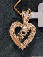 Close-up front view of the 10K gold heart-shaped MOM pendant with diamond accents.