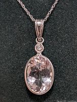 Front view of pendant showing oval morganite and round diamond accent