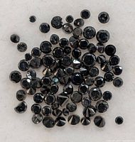 Close-up of assorted small black diamonds showing round faceted cuts and natural black color